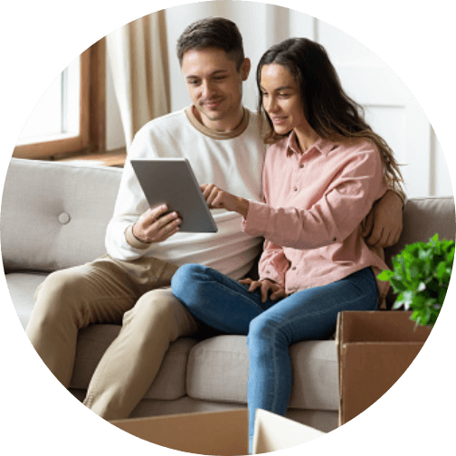 man and woman sitting on couch looking at smart tablet