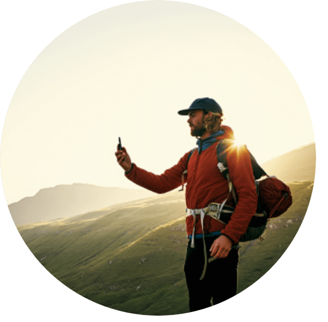 man hiking on mountain with hiking gear taking photo with smart phone