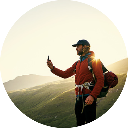 man hiking on mountain with hiking gear taking photo with smart phone