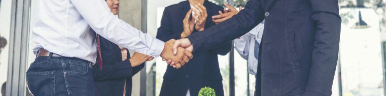 group of business people with two shaking hands and the rest clapping