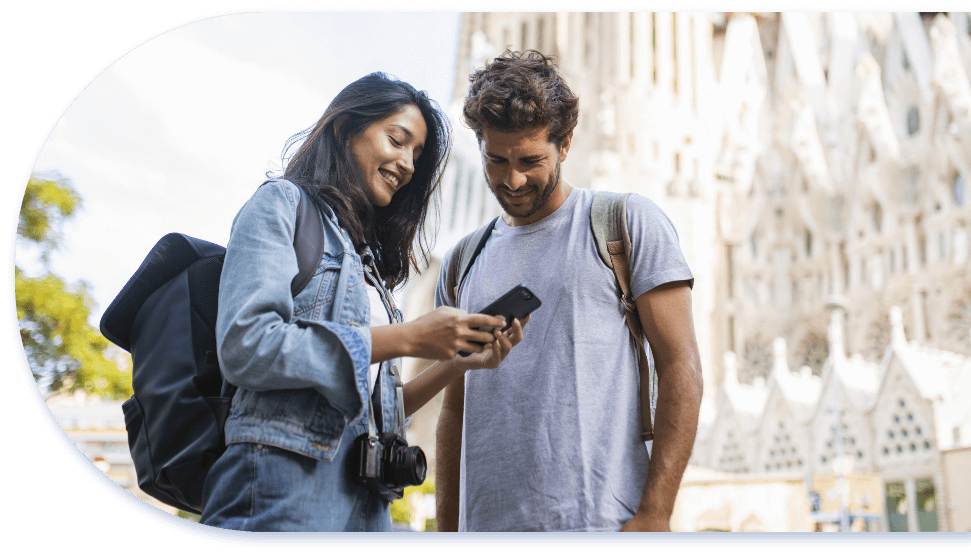man and woman outside grand building looking at smart phone smiling