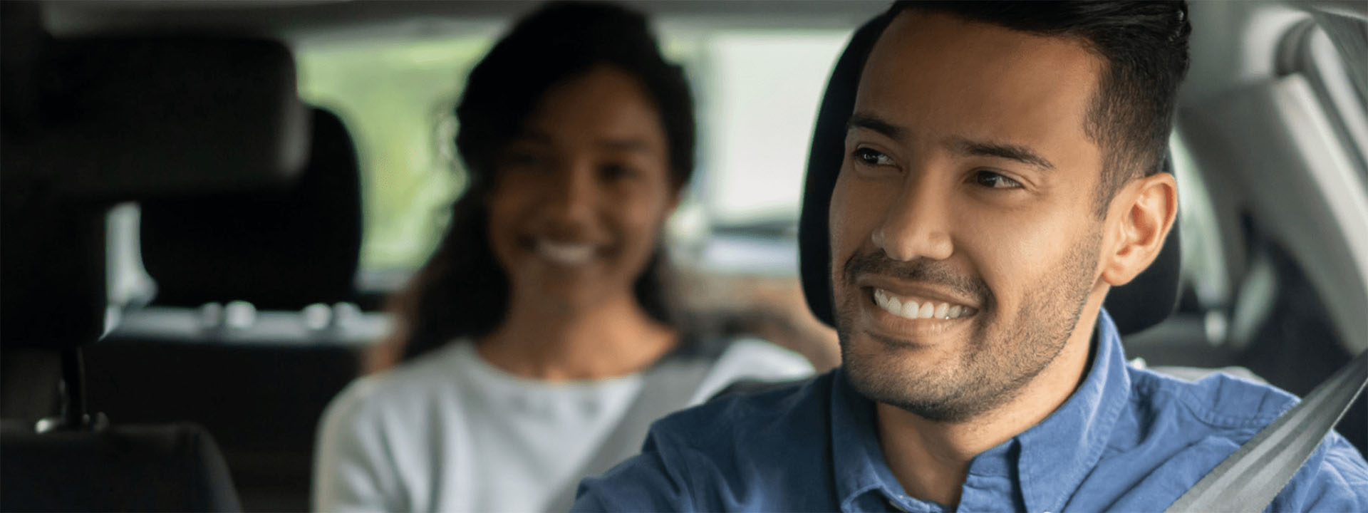 man in front seat with woman in back seat of car