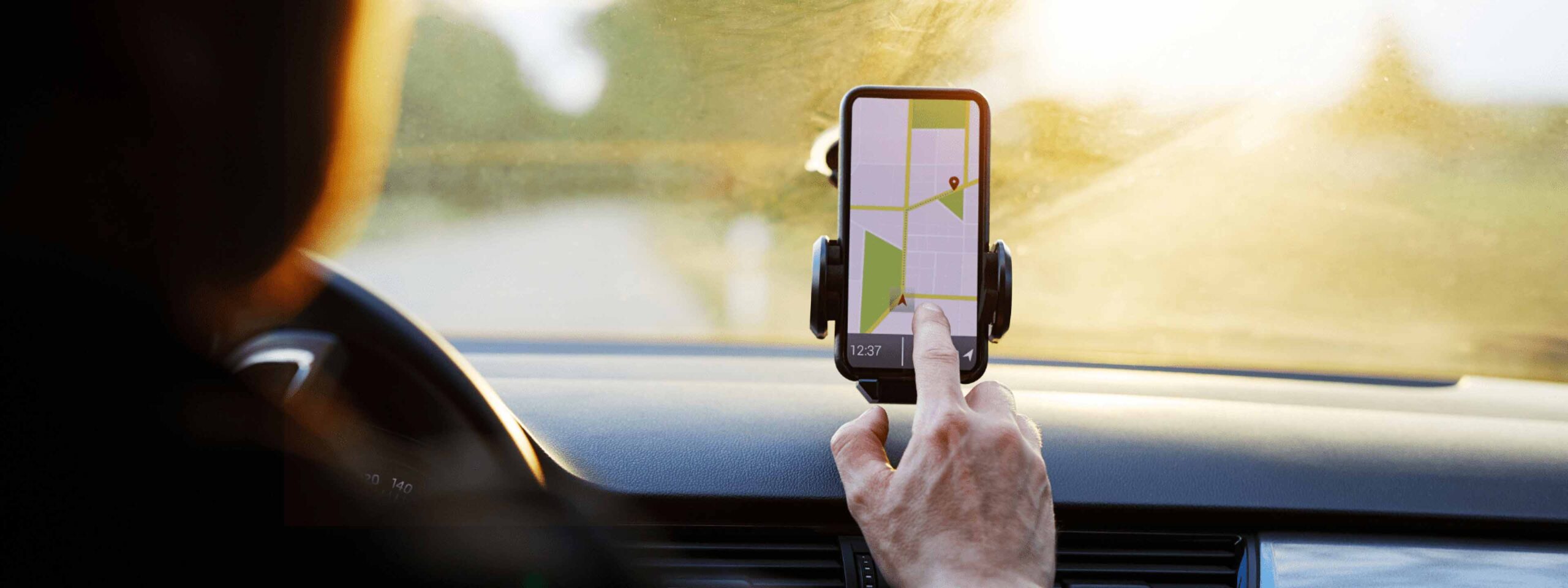 hand pointing to smart phone with map on screen in a vehicle