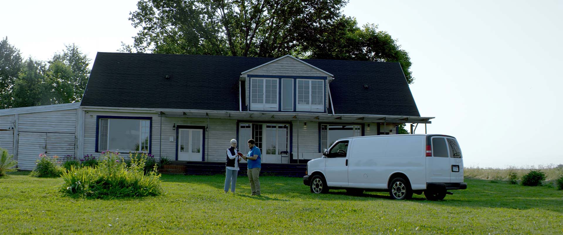 driver delivering package to a person with delivery van in front of house