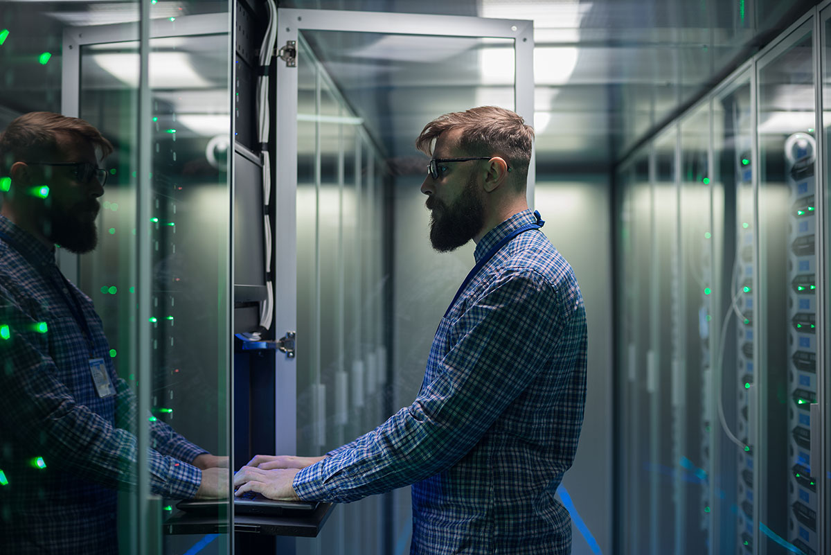 person standing and typing on keyboard in a server room