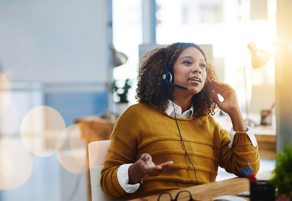 woman sitting at desk with headset on talking to customer