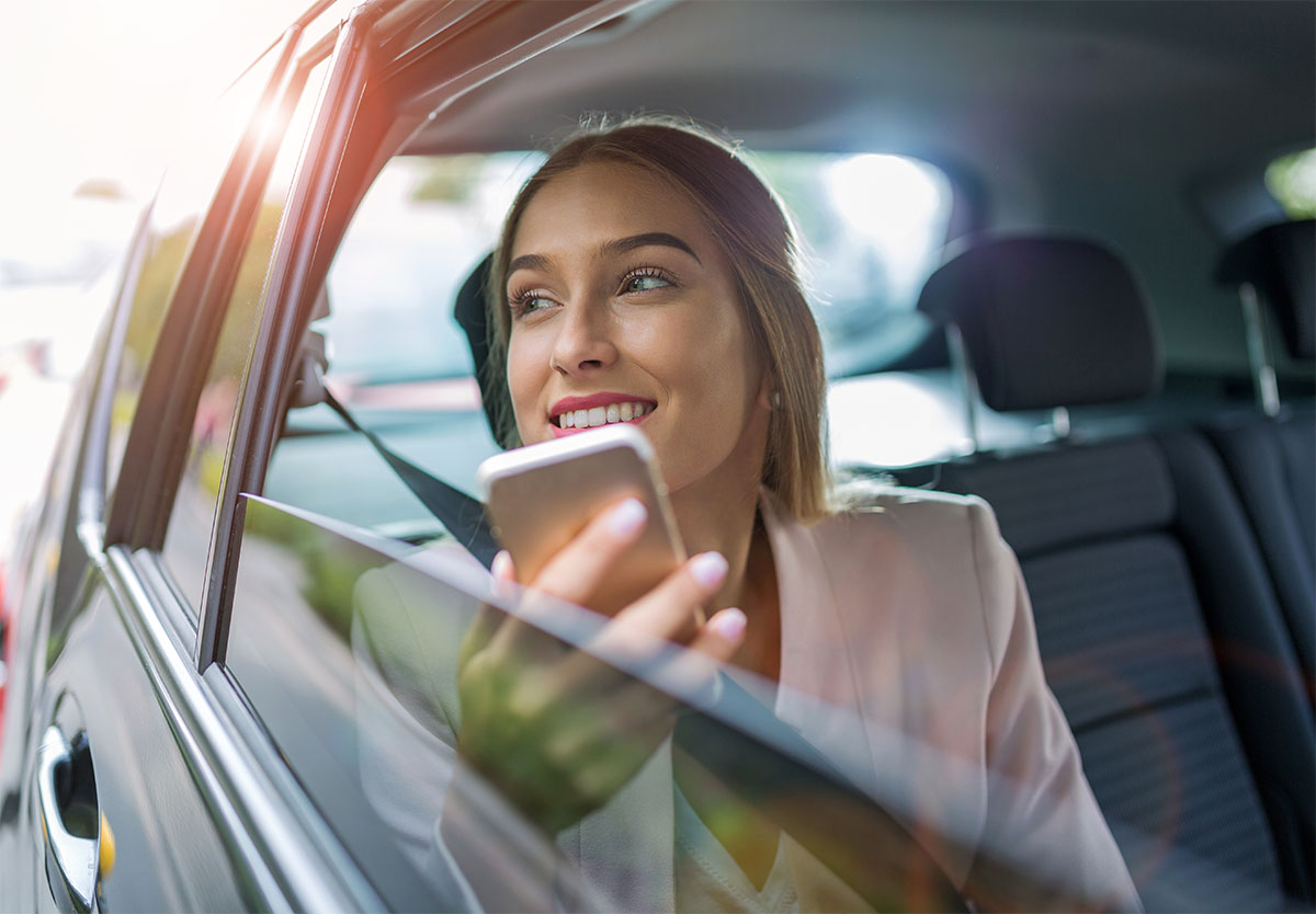 woman holding smart phone in backseat of car