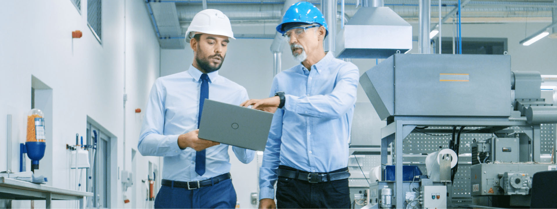 two engineers wearing hard hats looking at a laptop